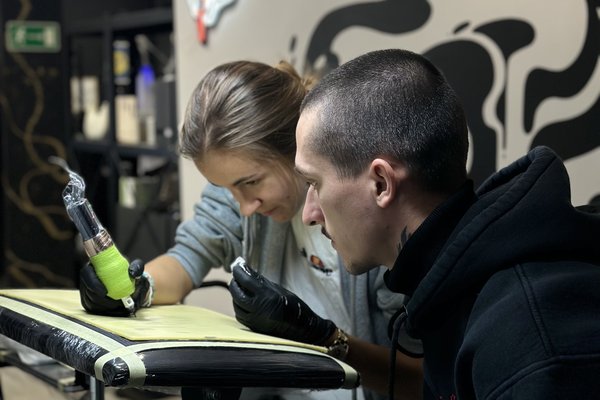 Hands-on tattoo course in Tallinn: student practices linework on artificial skin with a mentor’s guidance in a real studio, using professional equipment and strict hygiene.