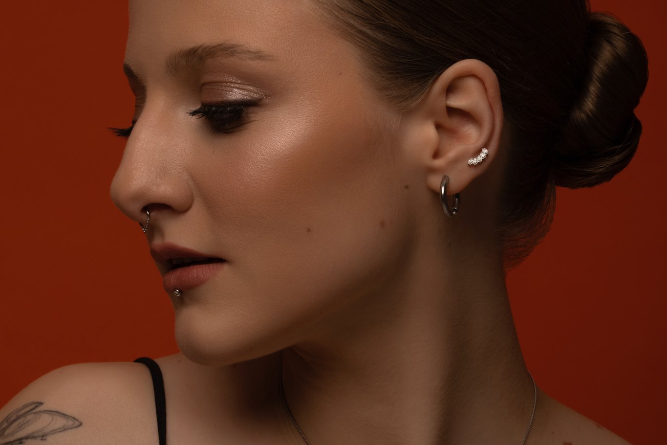 Näo- ja kõrvaaugustused (septum, labret, kõrvalest ja kõhreaugud) delikaatsete ehetega VEAN Tattoo stiilis Tallinnas.